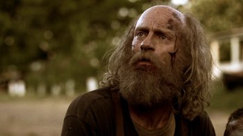 Movie still from “Z Nation” (2014), created by Karl Schaefer – An old man with a beard and a long beard looking to his left; Close Up shot, Low angle