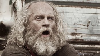 Movie still from “Z Nation” (2014), created by Karl Schaefer – An old man with long white hair and a long beard; Close Up shot, Low angle