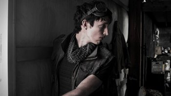 Movie still from “Z Nation” (2014), created by Karl Schaefer – A man wearing a leather jacket and goggles; Close Up shot, Low angle