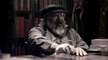 Movie still from “Z Nation” (2014), created by Karl Schaefer – An old man wearing a hat and glasses sitting at a table; Close Up shot, High angle
