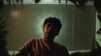 Movie still from “Creep 2” (2017), directed by Patrick Brice – A young man in a pink t - shirt is in front of a window; Close Up shot, Low angle