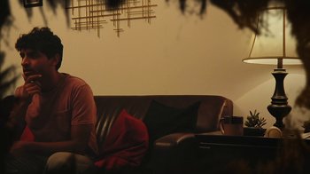 Movie still from “Creep 2” (2017), directed by Patrick Brice – A man sitting on a couch in a living room; Medium shot, Low angle