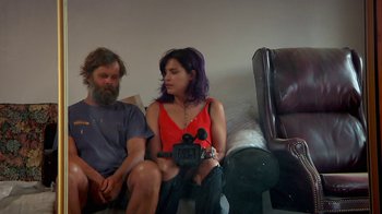 Movie still from “Creep 2” (2017), directed by Patrick Brice – A man and a woman sitting next to each other on a couch; Medium shot, High angle