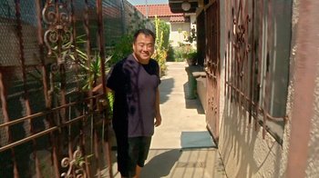 Movie still from “Creep 2” (2017), directed by Patrick Brice – A man standing on a sidewalk next to an iron gate; Wide shot, High angle