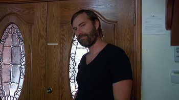 Movie still from “Creep 2” (2017), directed by Patrick Brice – A man standing in front of a wooden door; Medium shot, Low angle