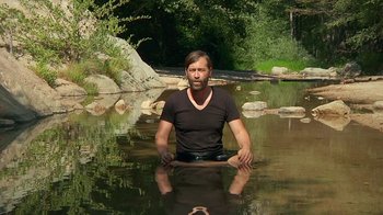 Movie still from “Creep 2” (2017), directed by Patrick Brice – A man sitting in the water in the middle of a body of water; Medium shot, High angle