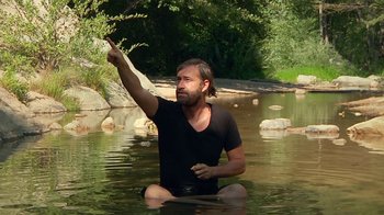 Movie still from “Creep 2” (2017), directed by Patrick Brice – A man sitting in the water with his hand raised; Medium shot, Low angle
