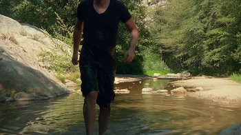 Movie still from “Creep 2” (2017), directed by Patrick Brice – A man is walking through a shallow river; Wide shot, High angle