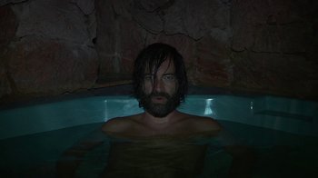 Movie still from “Creep 2” (2017), directed by Patrick Brice – A man with long hair is in a pool of water; Medium shot, High angle