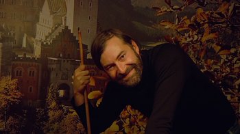 Movie still from “Creep 2” (2017), directed by Patrick Brice – A man with a beard holding a pair of pencils; Medium shot, Low angle