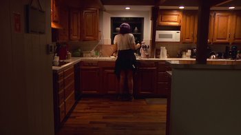 Movie still from “Creep 2” (2017), directed by Patrick Brice – A woman standing in a kitchen preparing a meal; Wide shot, High angle