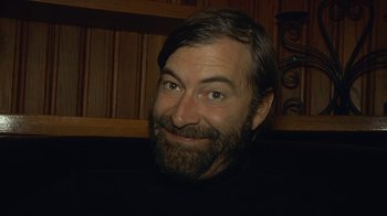 Movie still from “Creep 2” (2017), directed by Patrick Brice – A man with a goatee and beard smiling; Close Up shot, Low angle