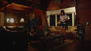 Movie still from “Creep 2” (2017), directed by Patrick Brice – Two people standing in a living room near a coffee table; Wide shot, Low angle