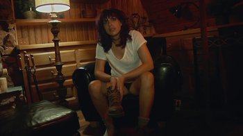 Movie still from “Creep 2” (2017), directed by Patrick Brice – A woman sitting on a chair holding a shoe; Medium shot, High angle