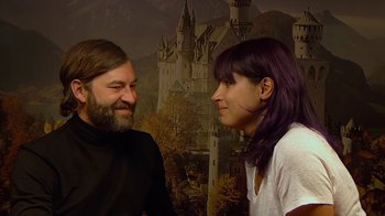 Movie still from “Creep 2” (2017), directed by Patrick Brice – A man and a woman standing next to each other in front of a castle mural; Close Up shot, Over the shoulder angle