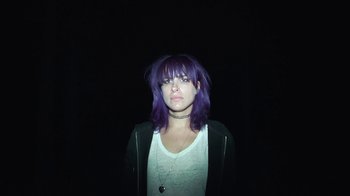 Movie still from “Creep 2” (2017), directed by Patrick Brice – A woman with purple hair standing in the dark; Close Up shot, Overhead angle