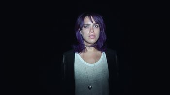 Movie still from “Creep 2” (2017), directed by Patrick Brice – A woman with purple hair standing in the dark; Close Up shot, Overhead angle
