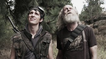 Movie still from “Z Nation” (2014), created by Karl Schaefer – Two men standing next to each other near a tree; Close Up shot, Low angle