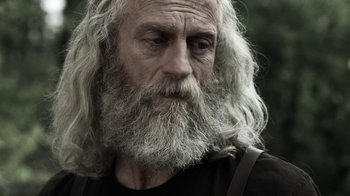 Movie still from “Z Nation” (2014), created by Karl Schaefer – An old man with long white hair and a beard; Close Up shot, Low angle