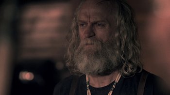 Movie still from “Z Nation” (2014), created by Karl Schaefer – An older man with long hair and a beard; Close Up shot, Over the shoulder angle