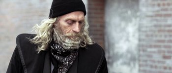 Movie still from “Z Nation” (2014), created by Karl Schaefer – A man with long white hair and a beard wearing a hat; Close Up shot, Low angle