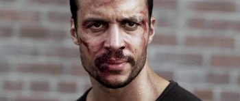 Movie still from “Z Nation” (2014), created by Karl Schaefer – A person with blood all over his face; Close Up shot, Low angle