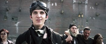 Movie still from “Z Nation” (2014), created by Karl Schaefer – A young man wearing a leather jacket and goggles; Close Up shot, Low angle