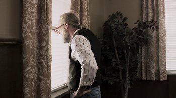 Movie still from “Z Nation” (2014), created by Karl Schaefer – A man standing in front of a window looking outside; Medium shot, Low angle