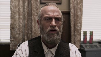 Movie still from “Z Nation” (2014), created by Karl Schaefer – An old man with a beard and a white shirt; Close Up shot, Low angle
