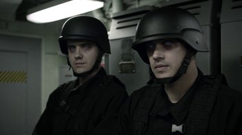 Movie still from “Z Nation” (2014), created by Karl Schaefer – A couple of men in black uniforms and helmets; Close Up shot, Over the shoulder angle