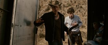 Movie still from “Zombieland” (2009), directed by Ruben Fleischer – A man wearing a cowboy hat standing next to another man in a field; Medium shot, Over the shoulder angle