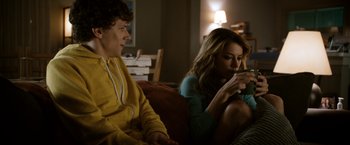 Movie still from “Zombieland” (2009), directed by Ruben Fleischer – Two people sitting on a couch looking at a cell phone; Medium shot, Over the shoulder angle