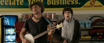 Movie still from “Zombieland” (2009), directed by Ruben Fleischer – A man playing a guitar while another man holds a guitar; Medium shot, Over the shoulder angle