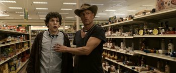 Movie still from “Zombieland” (2009), directed by Ruben Fleischer – A man in a cowboy hat standing next to another man in a store; Medium shot, Over the shoulder angle