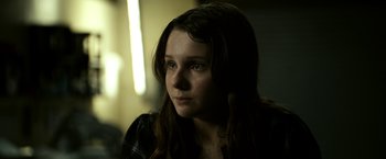 Movie still from “Zombieland” (2009), directed by Ruben Fleischer – A young girl is sitting in a dark room; Close Up shot, Over the shoulder angle