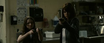 Movie still from “Zombieland” (2009), directed by Ruben Fleischer – Two women are playing a video game in a kitchen; Medium shot, Over the shoulder angle