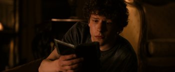 Movie still from “Zombieland” (2009), directed by Ruben Fleischer – A young man is reading a book in the dark; Close Up shot, Over the shoulder angle
