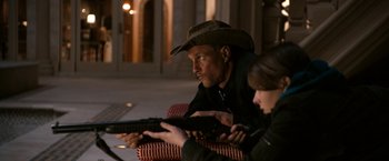 Movie still from “Zombieland” (2009), directed by Ruben Fleischer – A man and a woman sitting next to each other holding guns; Medium shot, Over the shoulder angle
