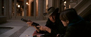 Movie still from “Zombieland” (2009), directed by Ruben Fleischer – A man in a cowboy hat is looking at a cell phone; Medium shot, Over the shoulder angle