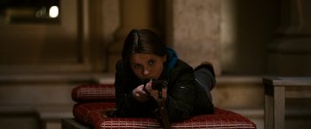 Movie still from “Zombieland” (2009), directed by Ruben Fleischer – A young girl laying on the ground holding a gun; Medium shot, High angle