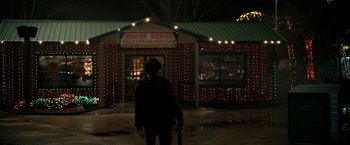 Movie still from “Zombieland” (2009), directed by Ruben Fleischer – A person standing in front of a building at night; Wide shot, Over the shoulder angle