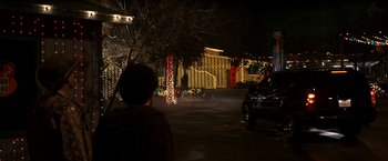Movie still from “Zombieland” (2009), directed by Ruben Fleischer – A man sitting in the back of a car in a parking lot at night; Extreme Wide shot, Over the shoulder angle