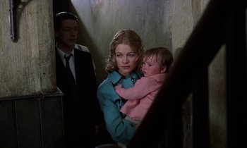 Movie still from “10 Rillington Place” (1971), directed by Richard Fleischer – A woman holding a baby in her arms while standing next to a man; Medium shot, Over the shoulder angle