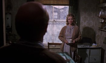 Movie still from “10 Rillington Place” (1971), directed by Richard Fleischer – A woman standing in front of a window holding a cup; Medium shot, Over the shoulder angle