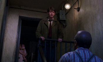 Movie still from “10 Rillington Place” (1971), directed by Richard Fleischer – A man in a jacket and tie standing next to a railing; Medium shot, Over the shoulder angle