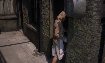 Movie still from “10 Rillington Place” (1971), directed by Richard Fleischer – A woman is standing outside of a brick building; Wide shot, High angle