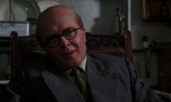 Movie still from “10 Rillington Place” (1971), directed by Richard Fleischer – A man in a suit and tie sitting in a chair; Close Up shot, Over the shoulder angle