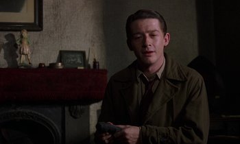 Movie still from “10 Rillington Place” (1971), directed by Richard Fleischer – A man in a trench coat holding a remote control; Close Up shot, Over the shoulder angle