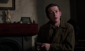 Movie still from “10 Rillington Place” (1971), directed by Richard Fleischer – A man in a trench coat is holding a remote control; Close Up shot, Over the shoulder angle