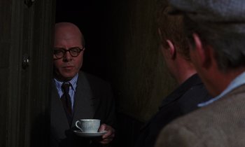 Movie still from “10 Rillington Place” (1971), directed by Richard Fleischer – A man holding a coffee cup in front of a mirror; Medium shot, Over the shoulder angle